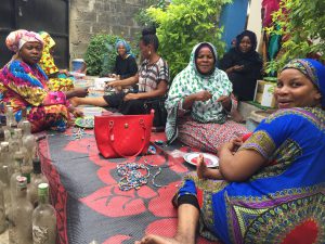 A group of African women making jewelry at a table