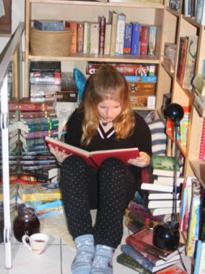 Ein Mädchen liest in einem Schrank voller Bücher.