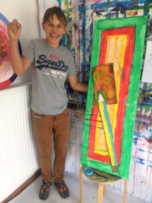 Ein aufgeregter Junge steht neben seinem bunten Gemälde